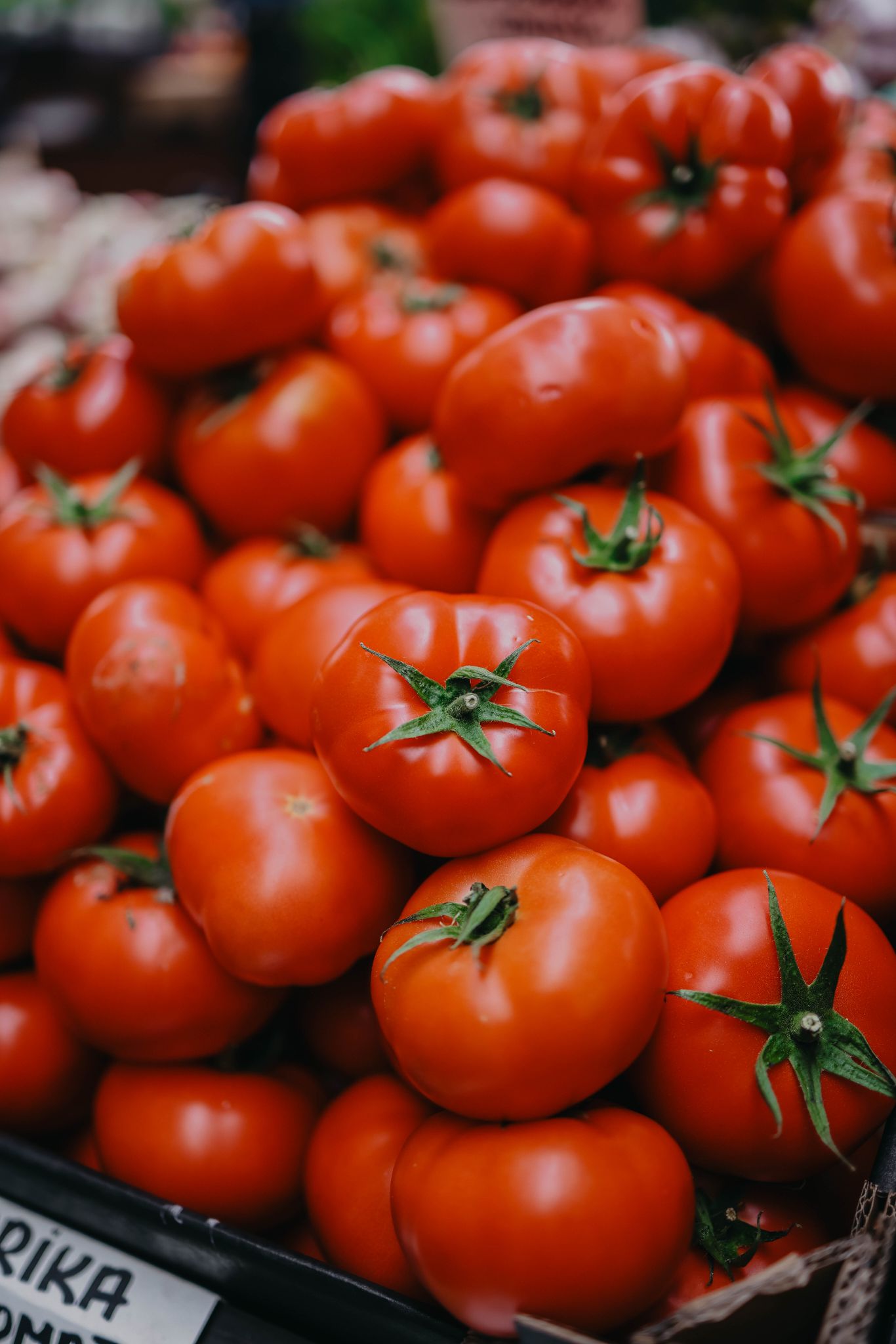 A vibrant display of ripe tomatoes stacked at a bustling local farmers' market.